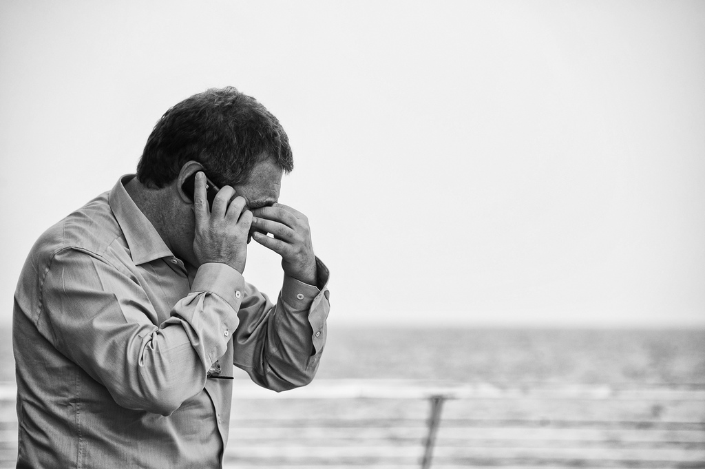 Man on the phone, stressed out on the beach. 